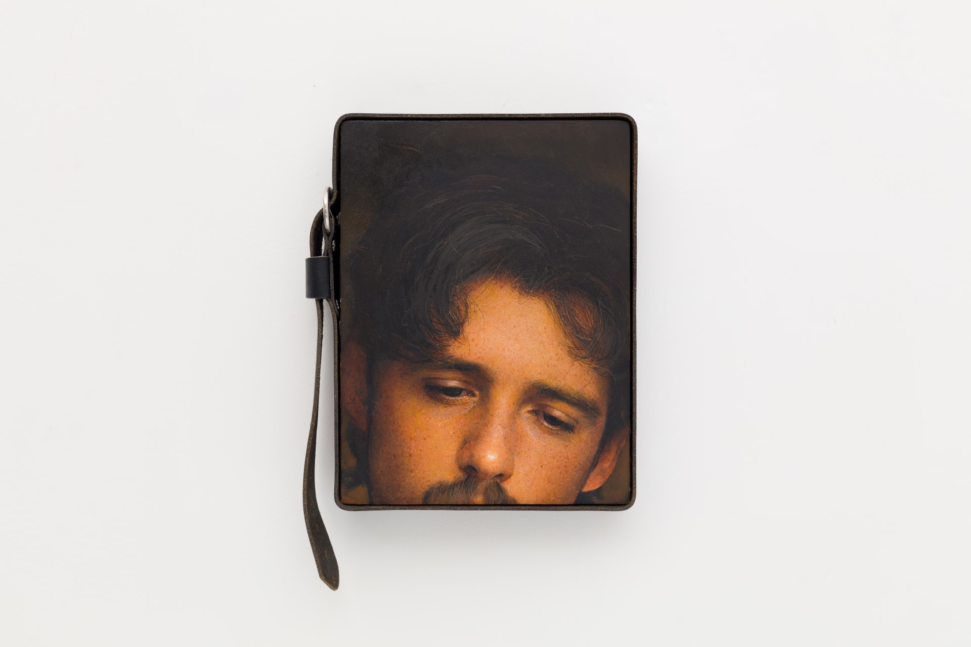 An oil on board painting framed by a leather belt by Ki Yoong depicting a close up crop of a moustached mans face