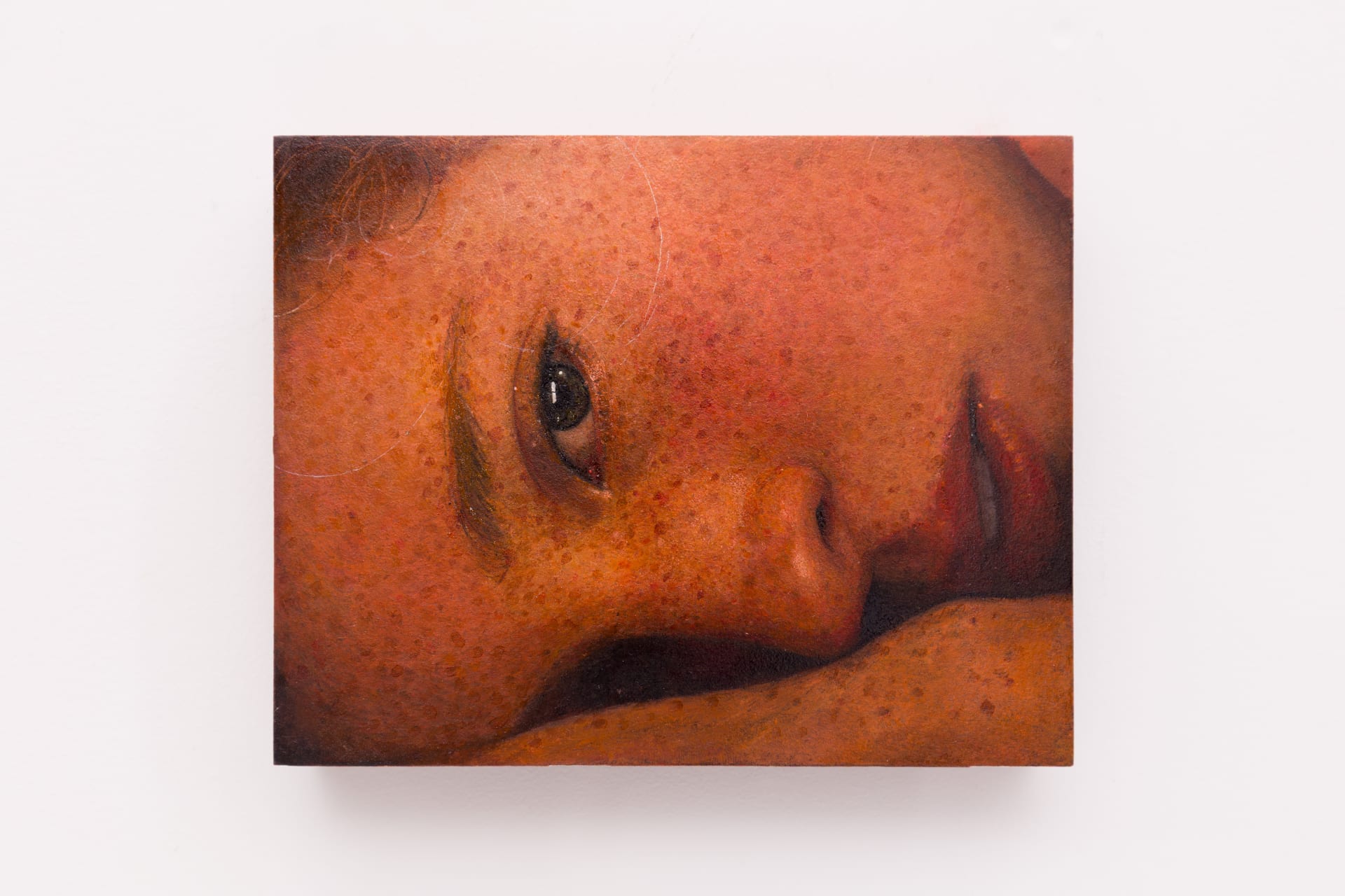A close-cropped oil on board portrait of a freckled young white woman lying on her side by Ki Yoong