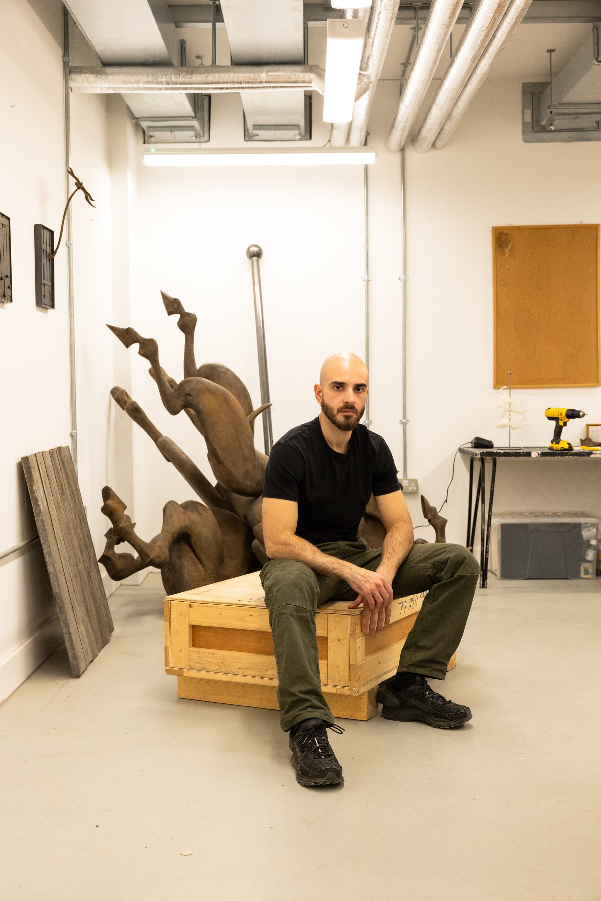 A portrait of Salvatore Pione sat on a wooden crate in his studio