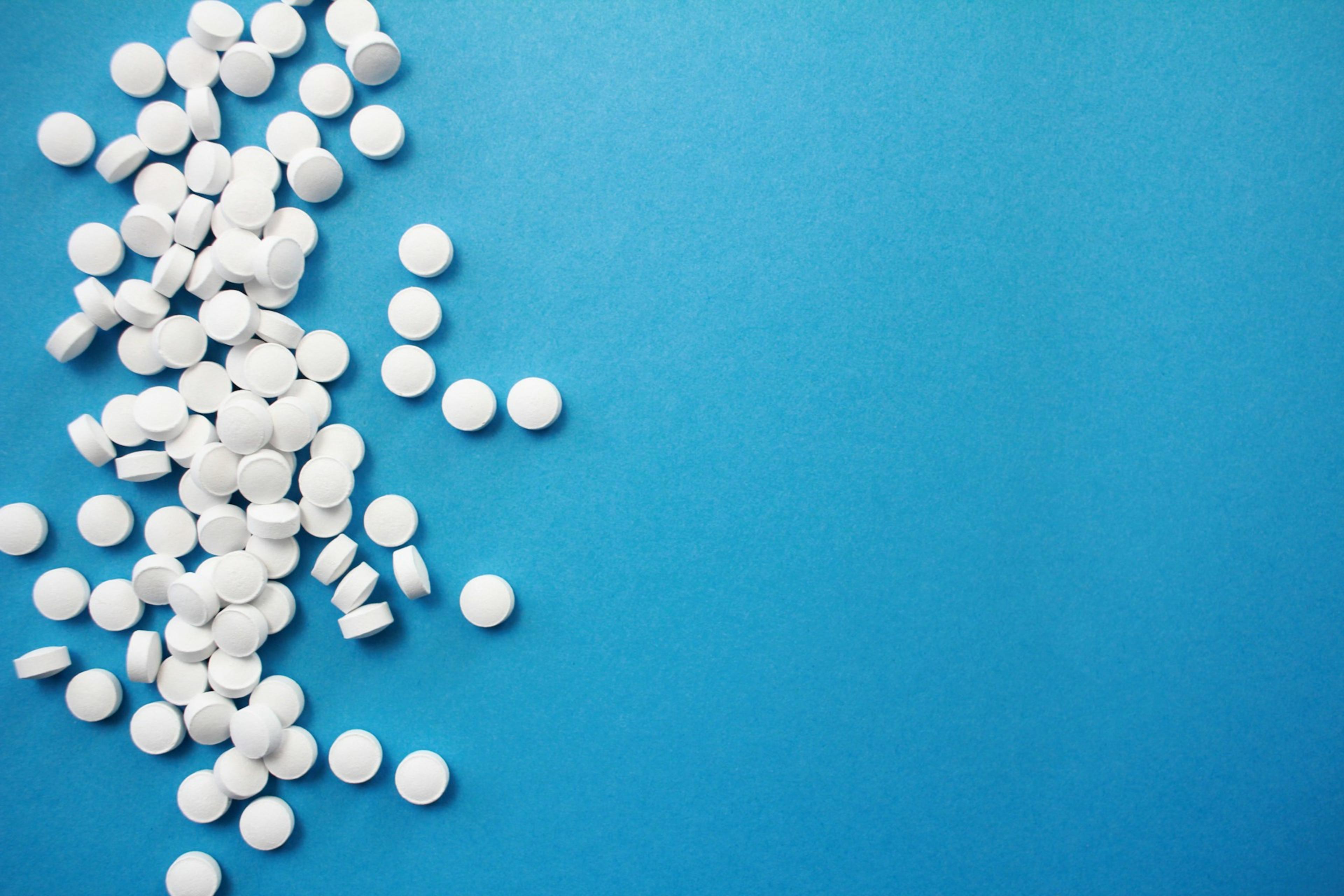 White pills scattered on a blue surface