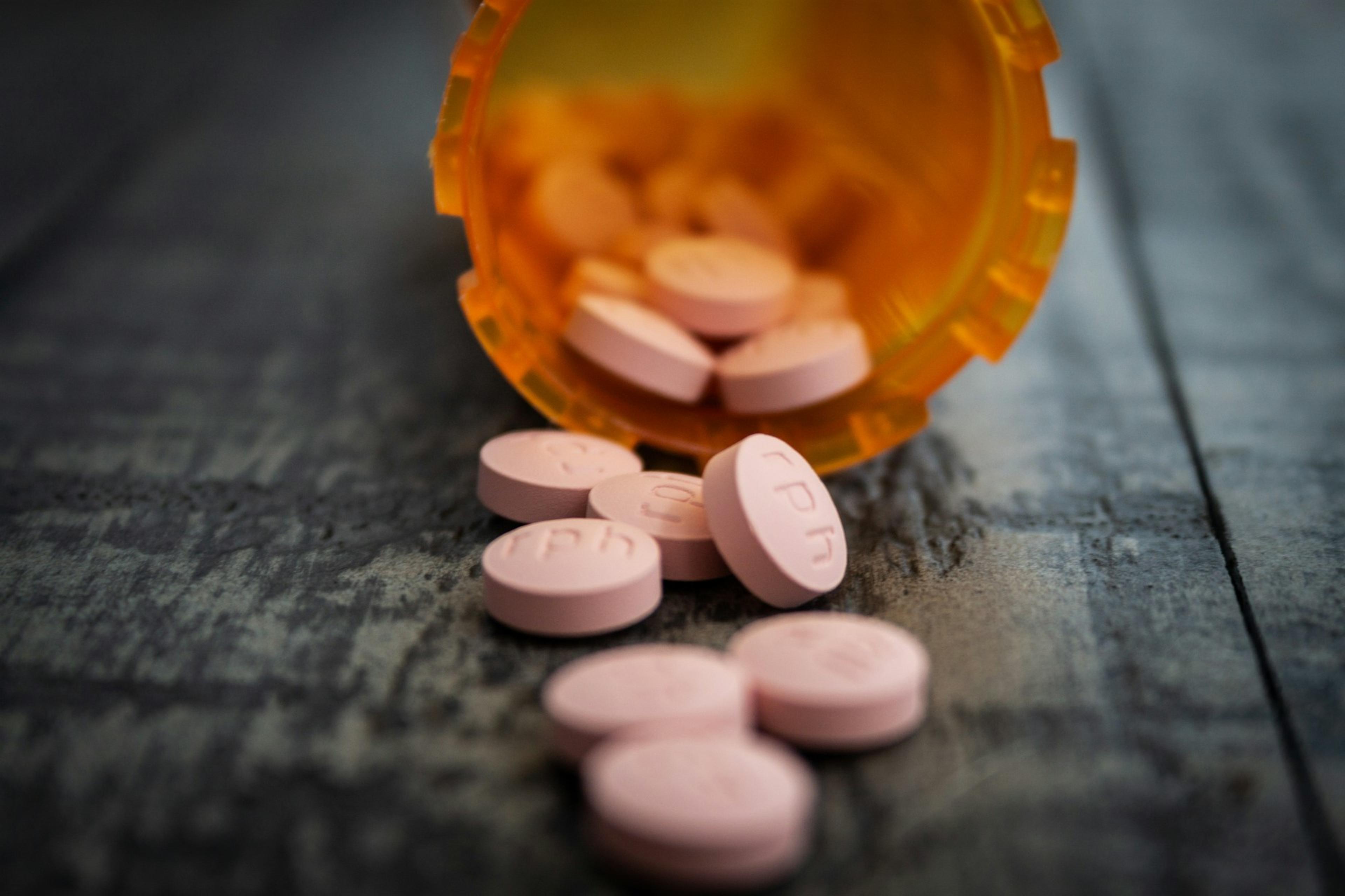 Picture of pills scattered on a surface from a plastic container