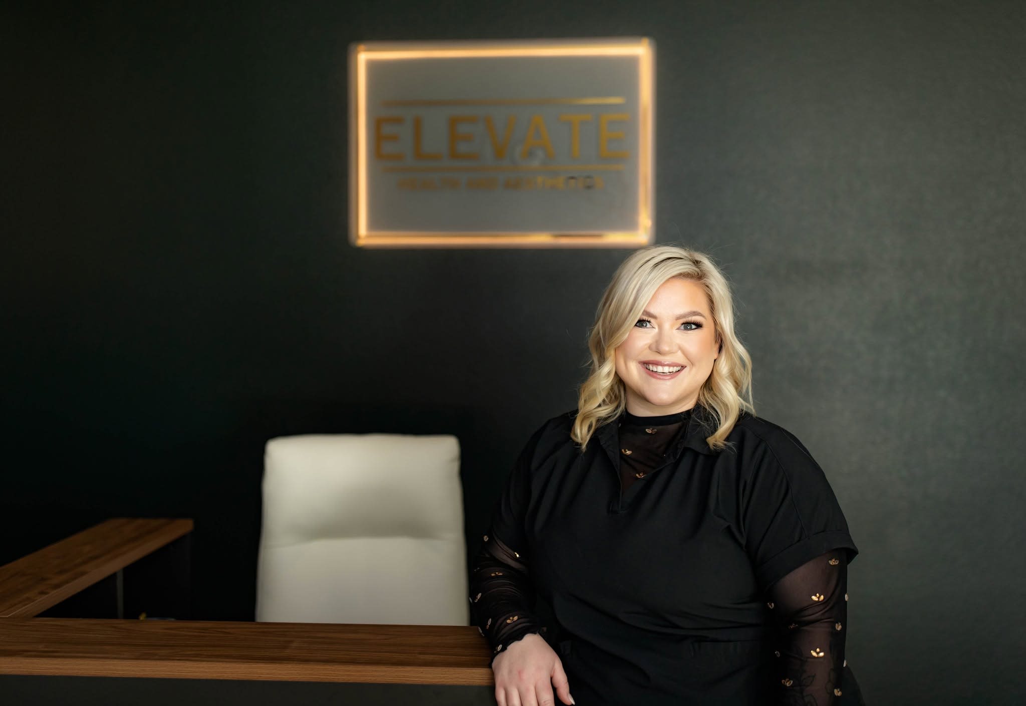 Sara Childress, Founder and Lead Provider at Elevate Health & Aesthetics, seated at her desk