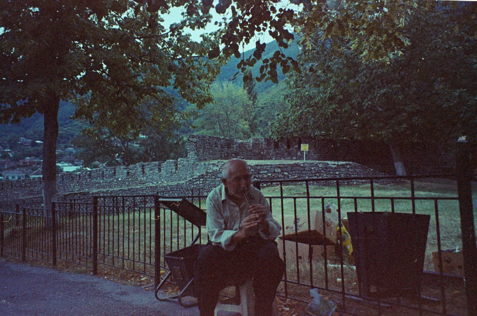 A man playing a flute next to Sheki Castle