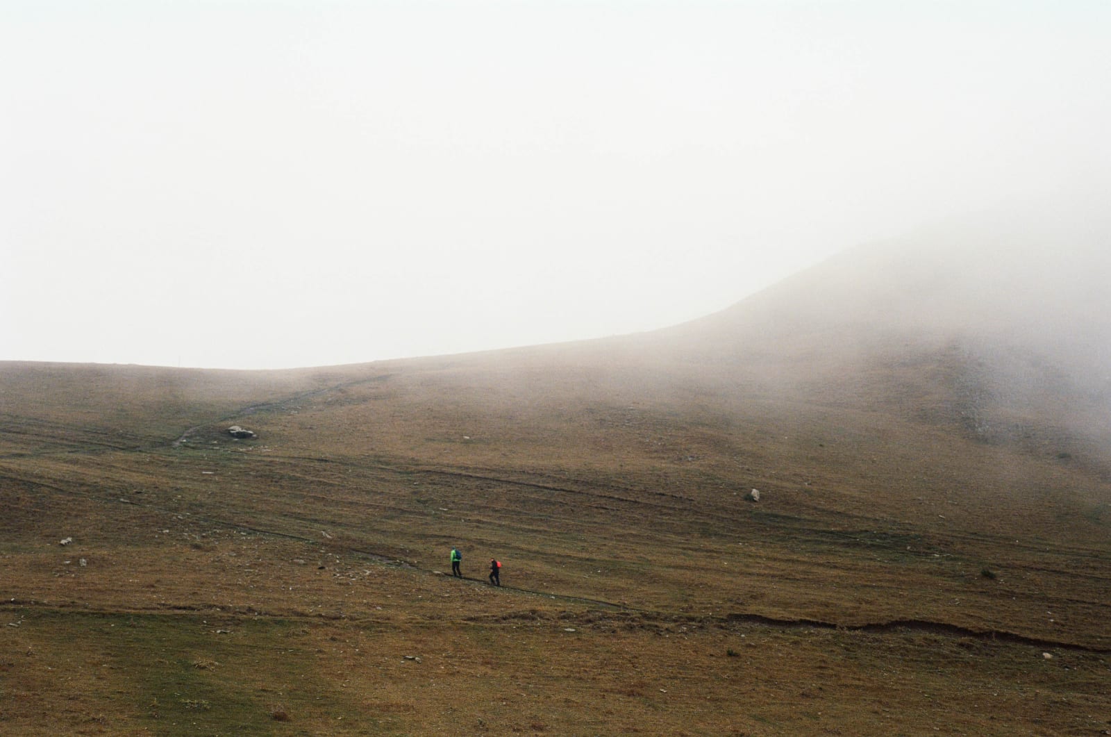 Two hikers in the fog climbing to the Gergeti Church