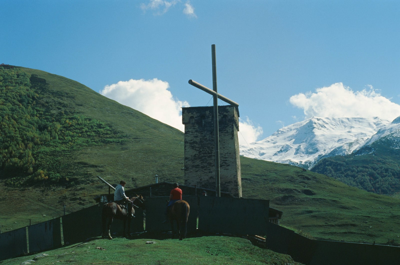 Two boys on horses in front of the Lamaria church in Ushguli