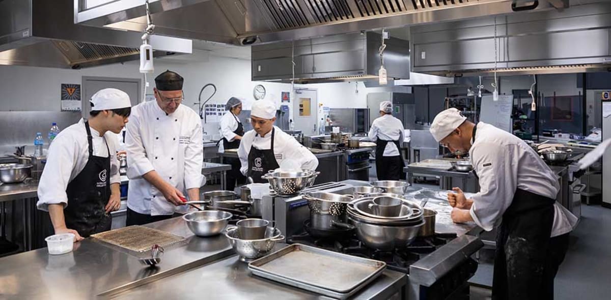 Tutor teaches students in a training kitchen.