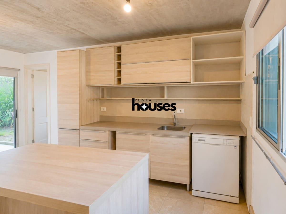 Bright integrated kitchen with light wood cabinetry and garden-facing windows