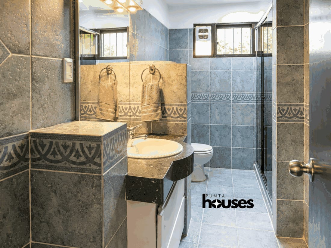 Full bathroom with blue tiled walls, vanity, toilet and glass walk-in shower