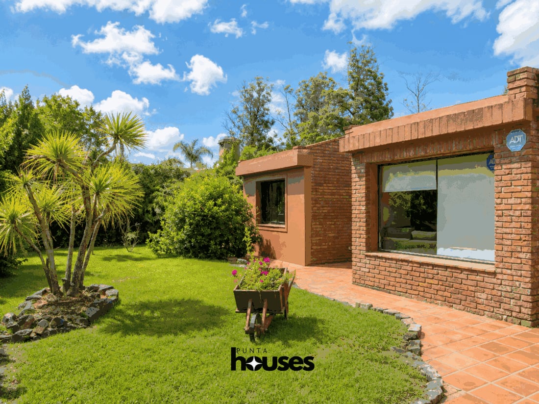 Landscaped front garden with mature trees, lawn and brick house in Punta del Este