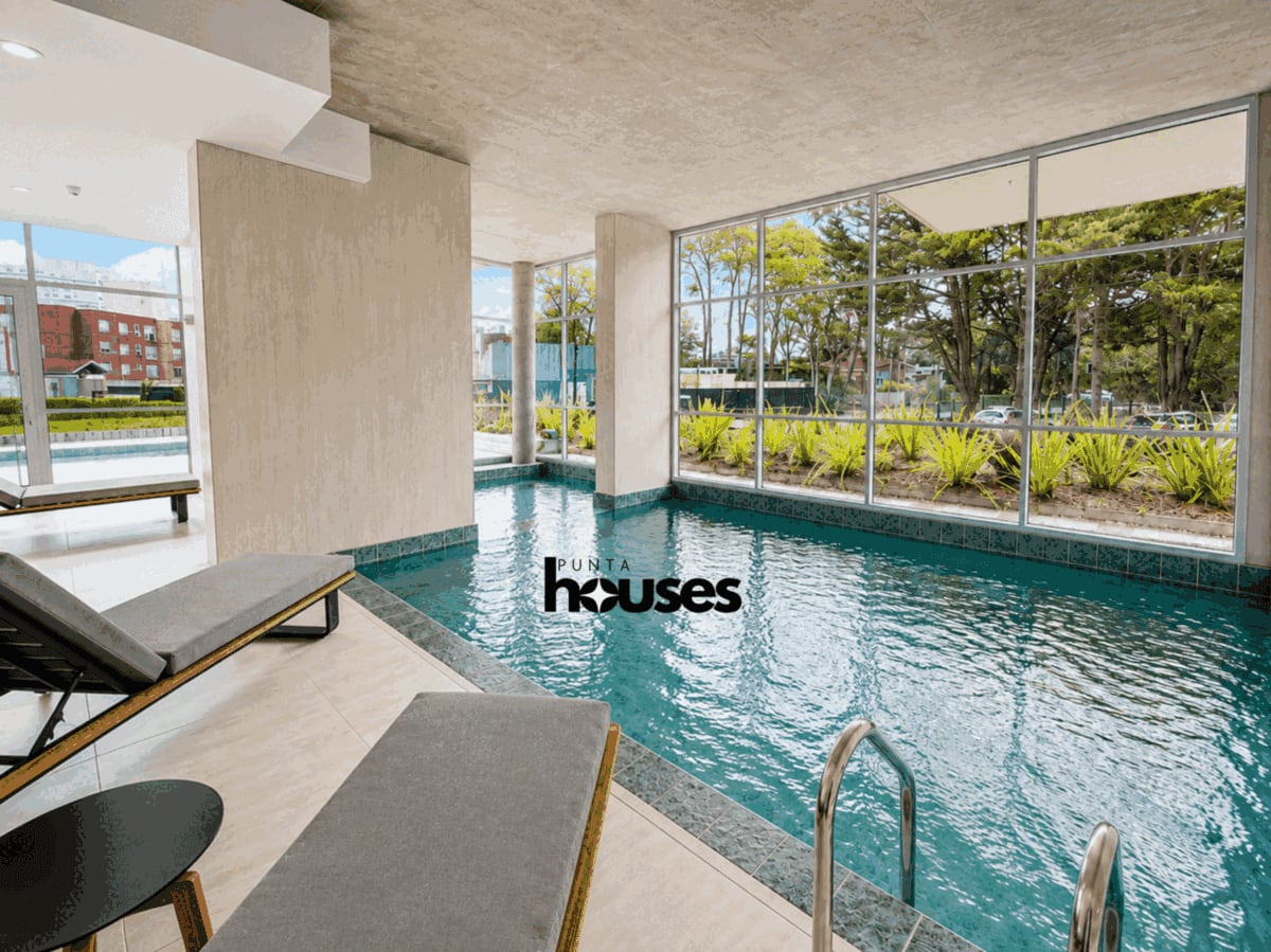 Bright indoor heated swimming pool surrounded by large windows and greenery, one of the premium amenities at View 2.