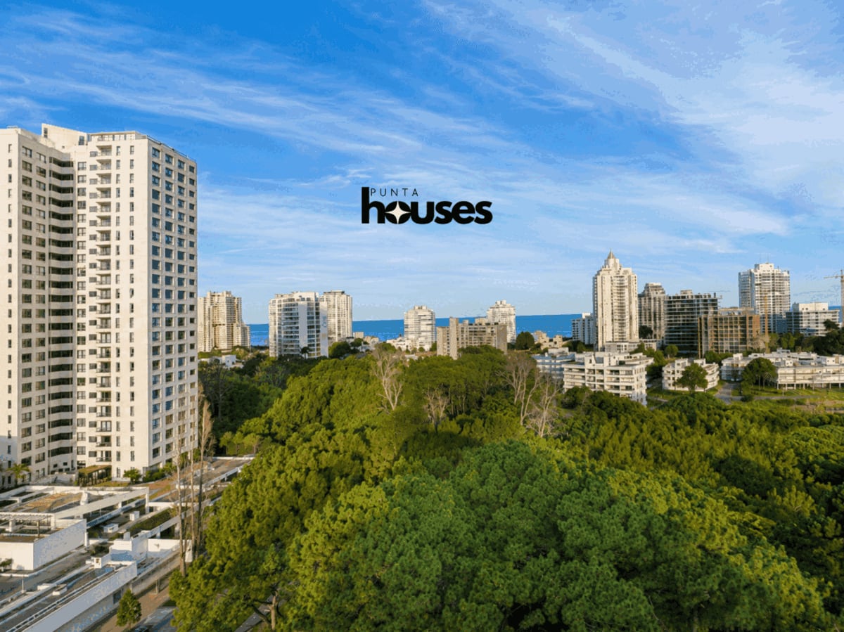 Elevated panoramic outlook combining mature greenery, the Punta del Este skyline and blue Atlantic Ocean.