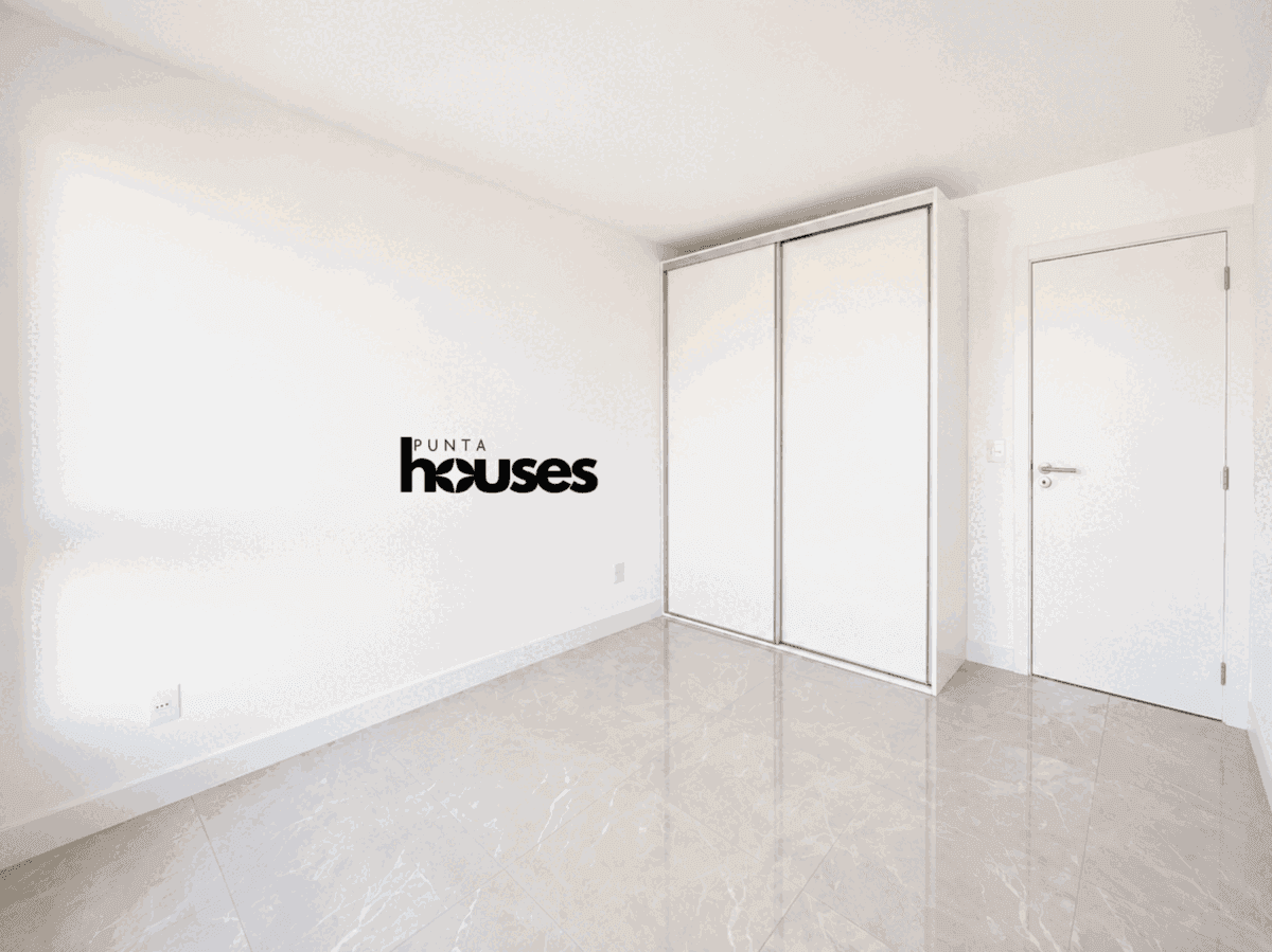 Modern bedroom with built-in wardrobe, neutral finishes and polished flooring in a newly completed Punta del Este apartment.