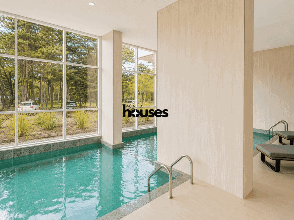 Contemporary indoor pool with large windows overlooking the landscaped surroundings of the building.