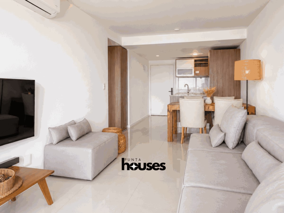 Furnished dining room with wooden table and neutral decor in apartment for sale in Roosevelt Punta del Este.