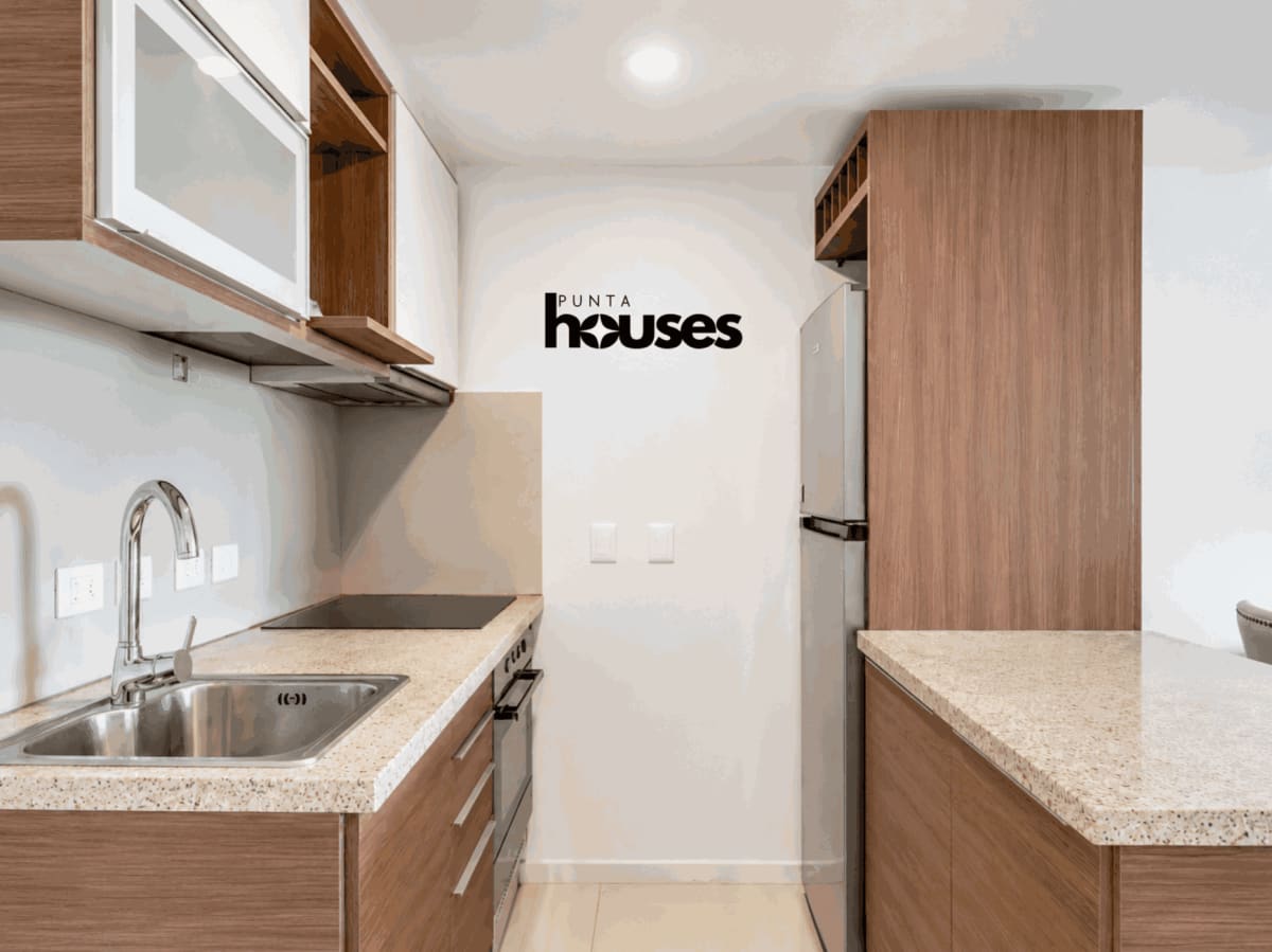 Contemporary kitchen with wood cabinets, stainless steel sink and stone countertops in Punta del Este apartment.