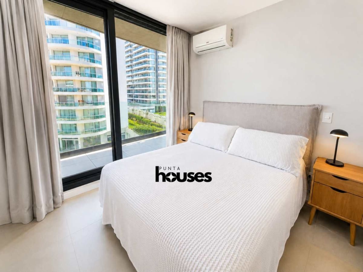 Bright one-bedroom apartment bedroom with large windows and balcony access at Manglar Brava Punta del Este.