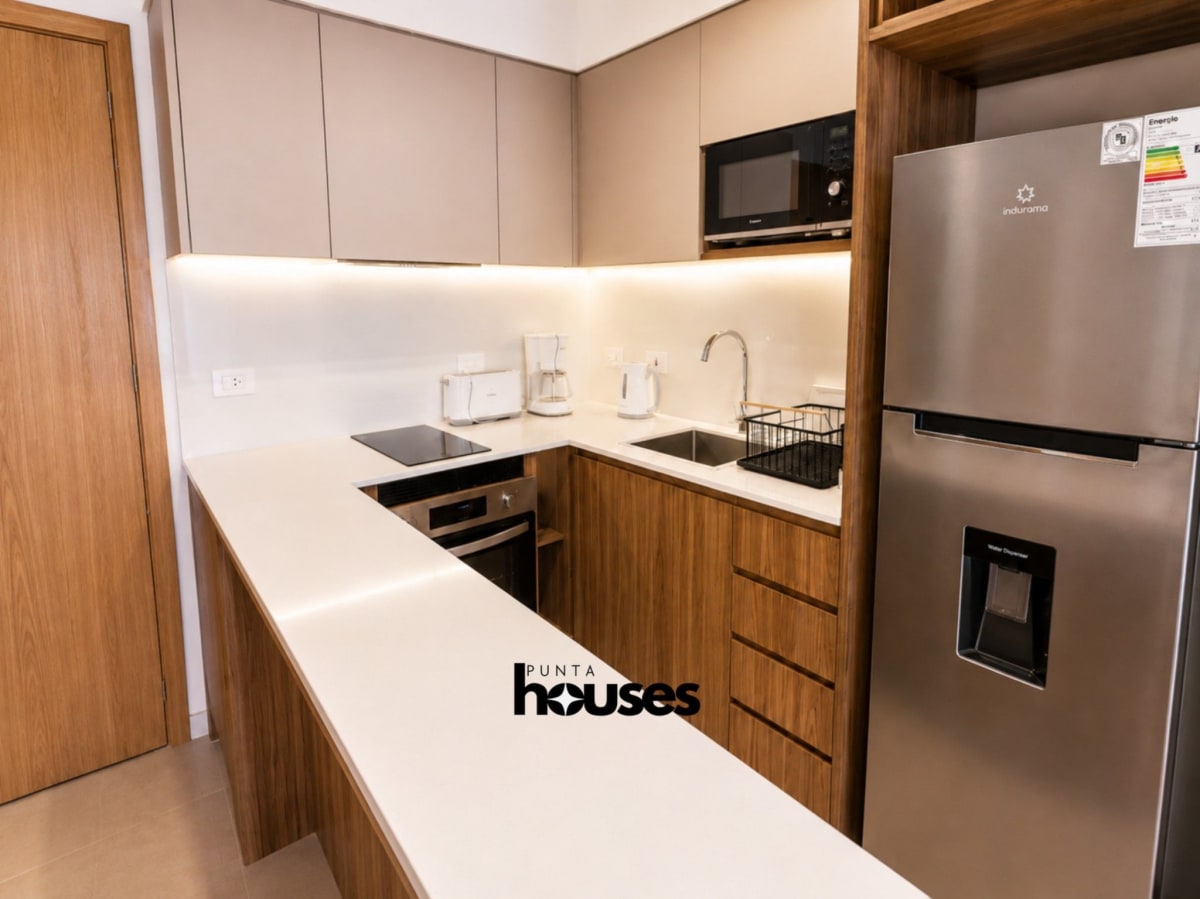 Modern equipped kitchen with wood cabinetry and integrated appliances in Manglar Brava apartment in Punta del Este.