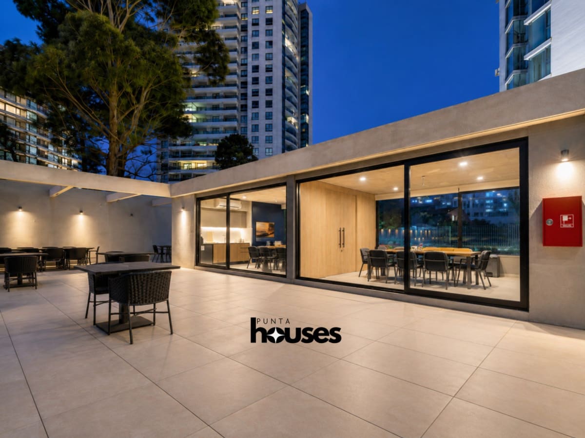 Illuminated outdoor communal terrace and barbecue spaces at Manglar Brava Punta del Este at dusk.