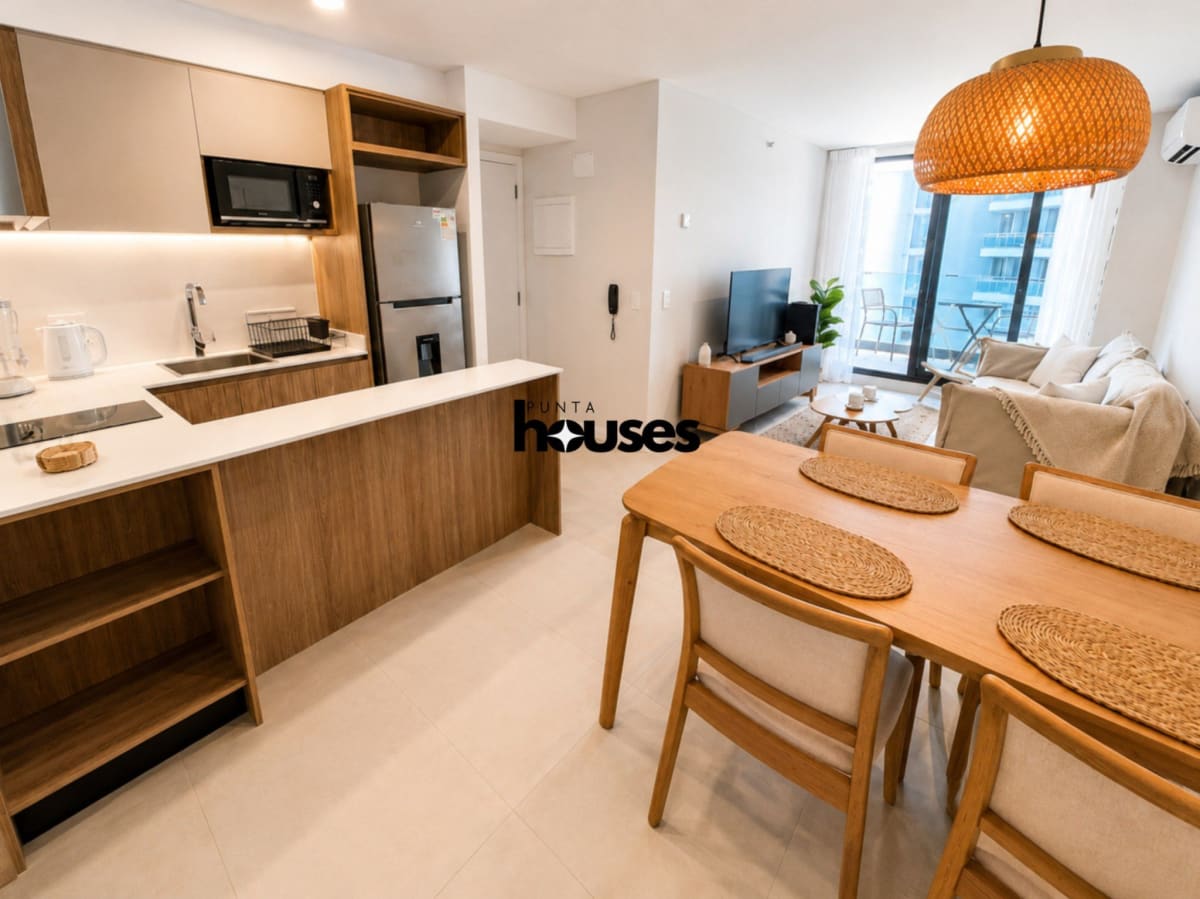 Furnished living room with dining area and open kitchen in one-bedroom Manglar Brava apartment for sale.