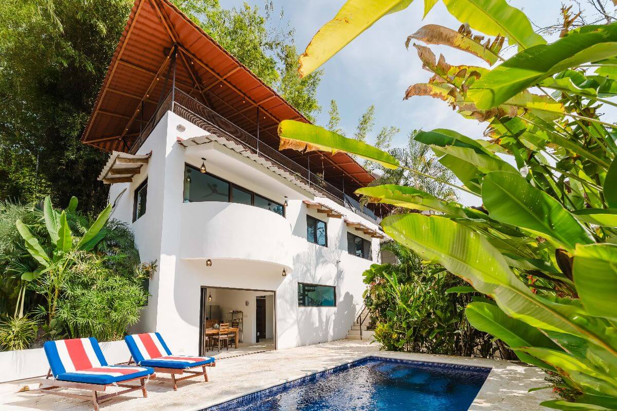 Modern white 3-bedroom Casa Iguana in Quepos, Costa Rica, with poolside view and tropical greenery