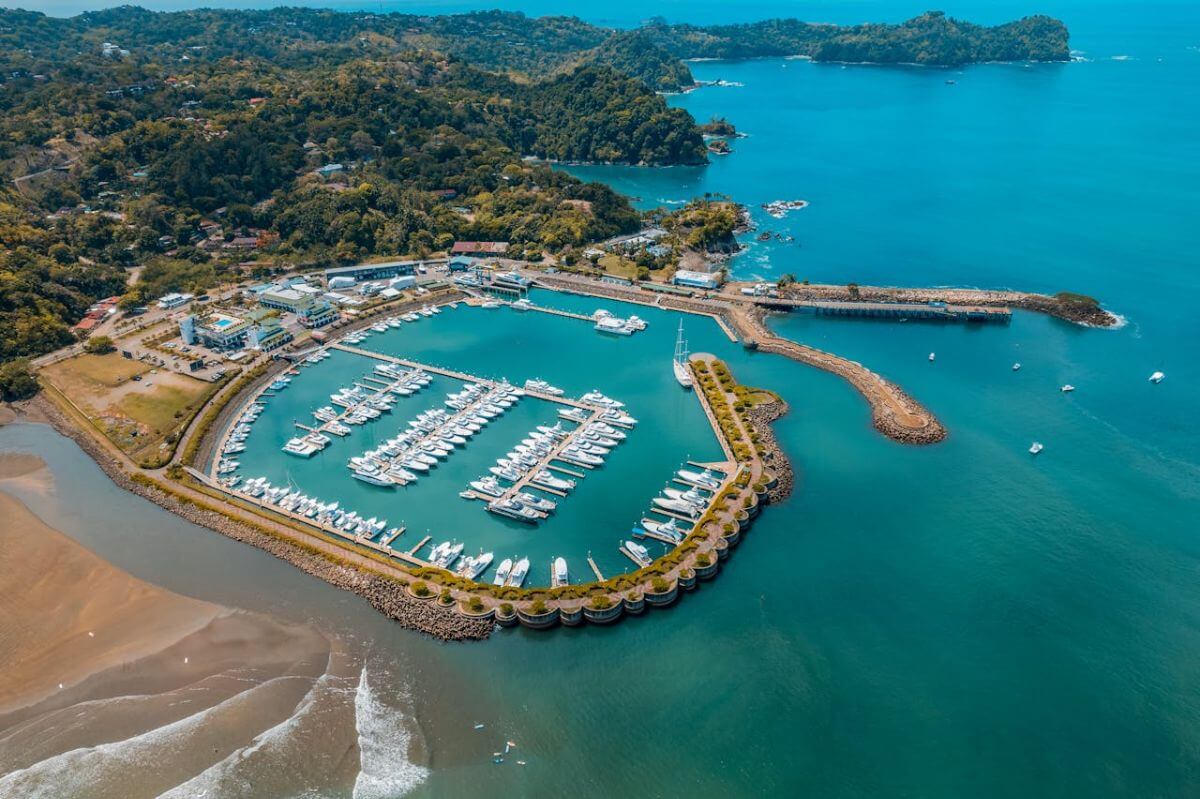 Aerial view of Marina Pez Vela in Quepos, Costa Rica, showing luxury yachts, turquoise waters, and surrounding lush landscape