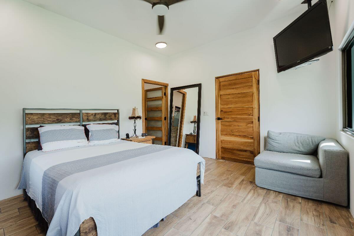 Spacious bedroom at Casa Iguana in Quepos, Costa Rica, featuring custom teak doors, natural light, and modern furnishings