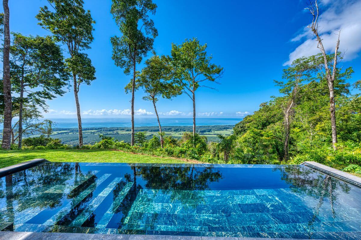 Panoramic ocean view from the infinity pool of Brisas del Mar in Quepos, Costa Rica, showcasing lush surroundings and distant coastline.