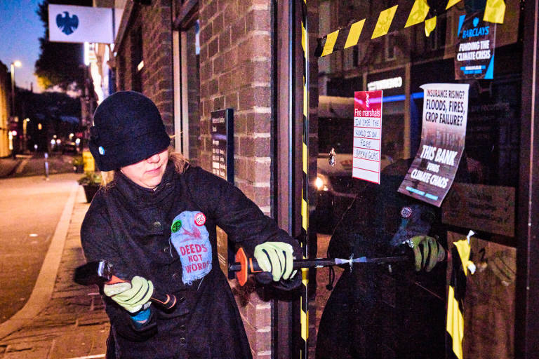 Extinction Rebellion co-founder Dr Gail Bradbrook breaks a window at Barclays Bank as part of XR&#039;s &quot;Money Rebellion&quot;. Photograph Copyright &copy; Simon Holliday