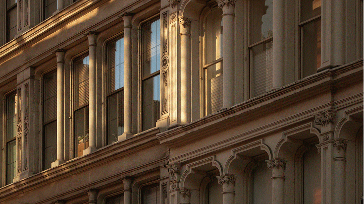 Ornate building facade with columns, arches, and windows, illuminated by warm, golden sunlight.
