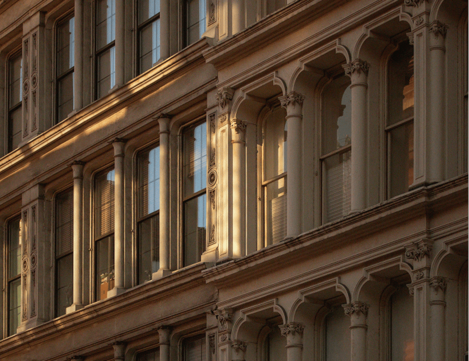 Ornate building facade with columns, arches, and windows, illuminated by warm, golden sunlight.
