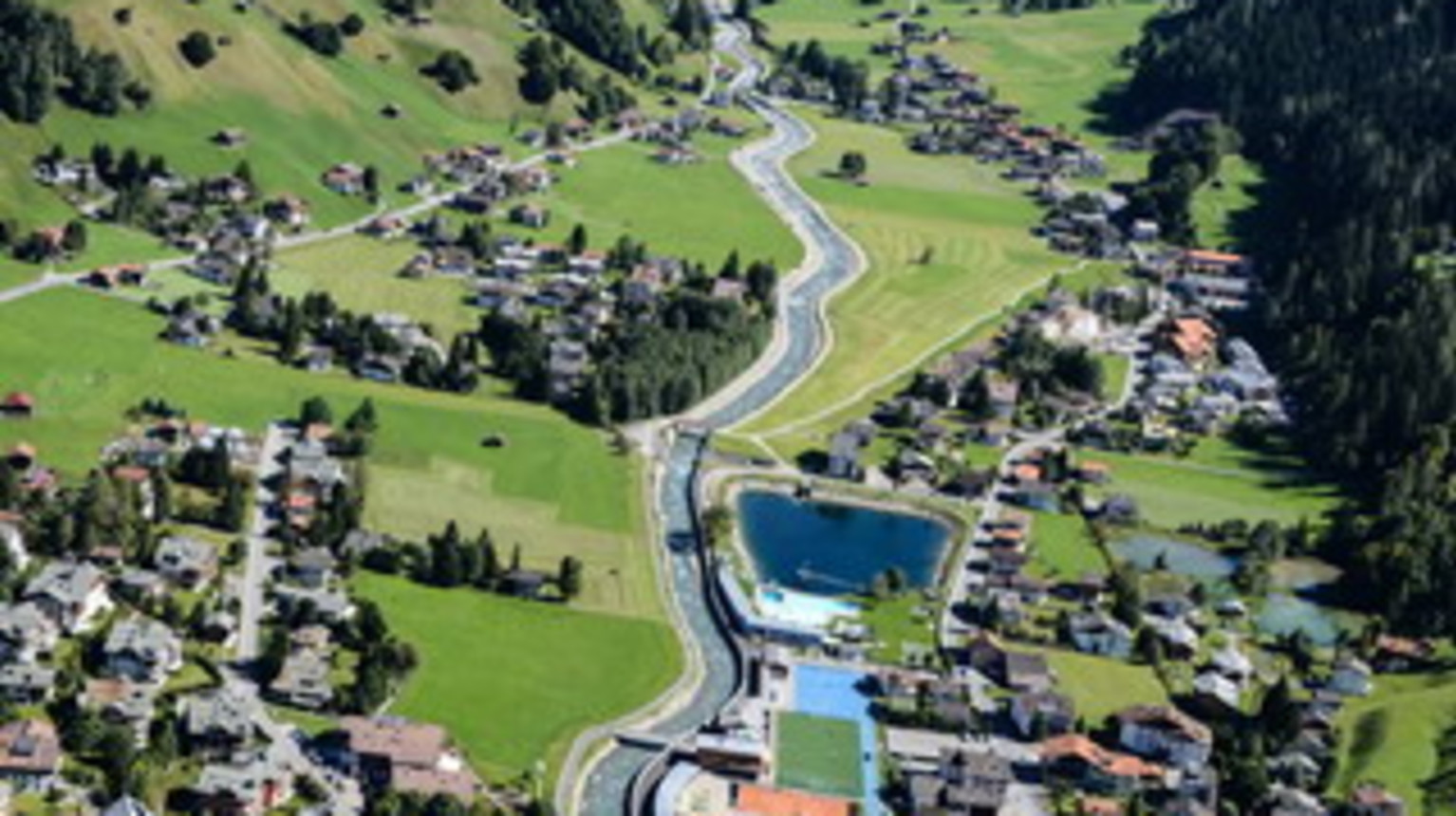 Klosters Platz/Brüggä/Doggiloch nach erfolgten Baumassnahmen. Auf der Fotografie sieht man das neue Bachbett der Landquart, das renovierte Freibad und die Überlaufbecken im Bereich Arena/Silvrettapark (Bild Gemeinde Klosters).