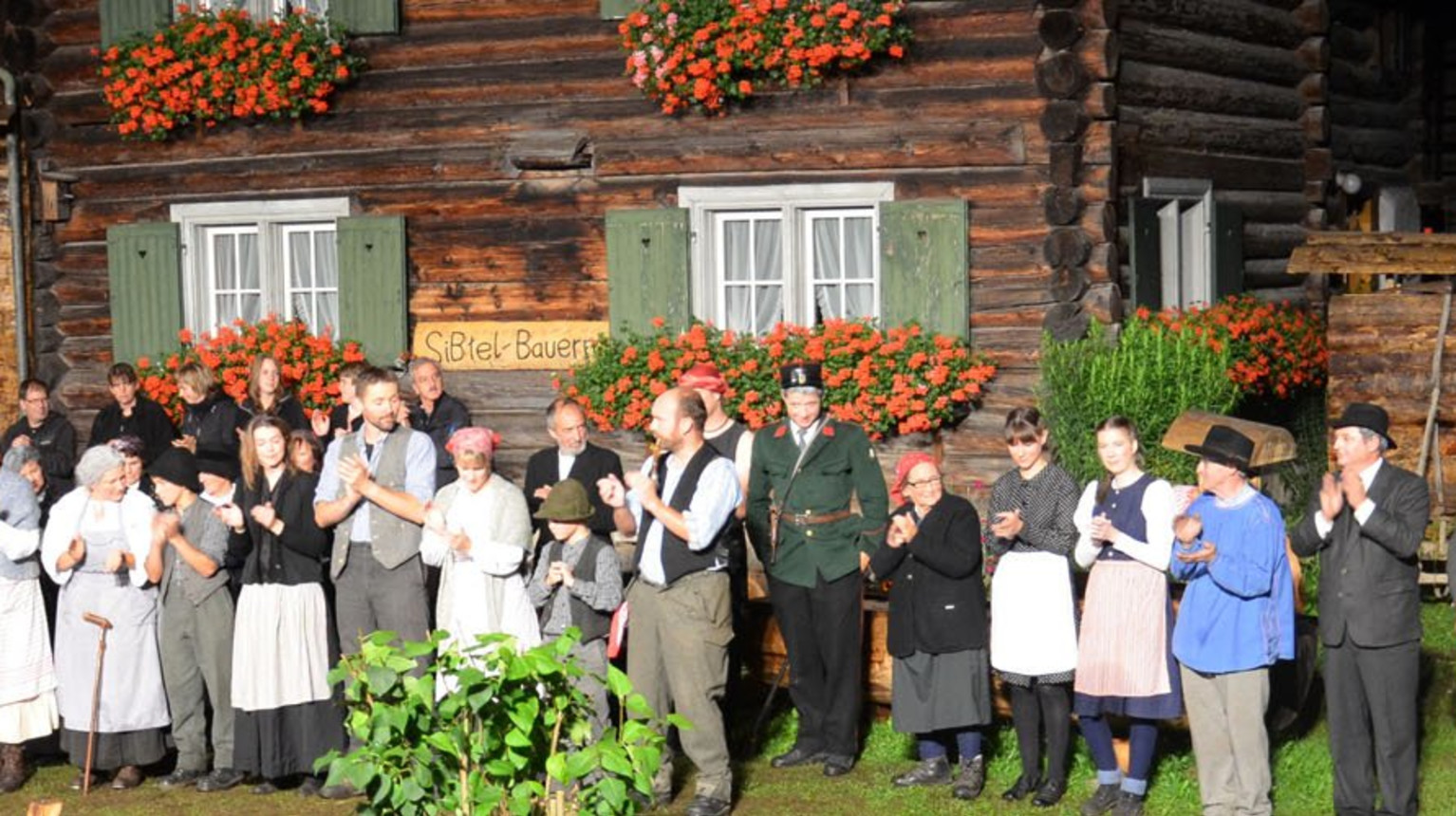 The Klosters-Serneus theatre group in front of the set for the play "Die Siebtel-Bauern" with the Wasenhaus (Klosters-Serneus theatre group, 2011).