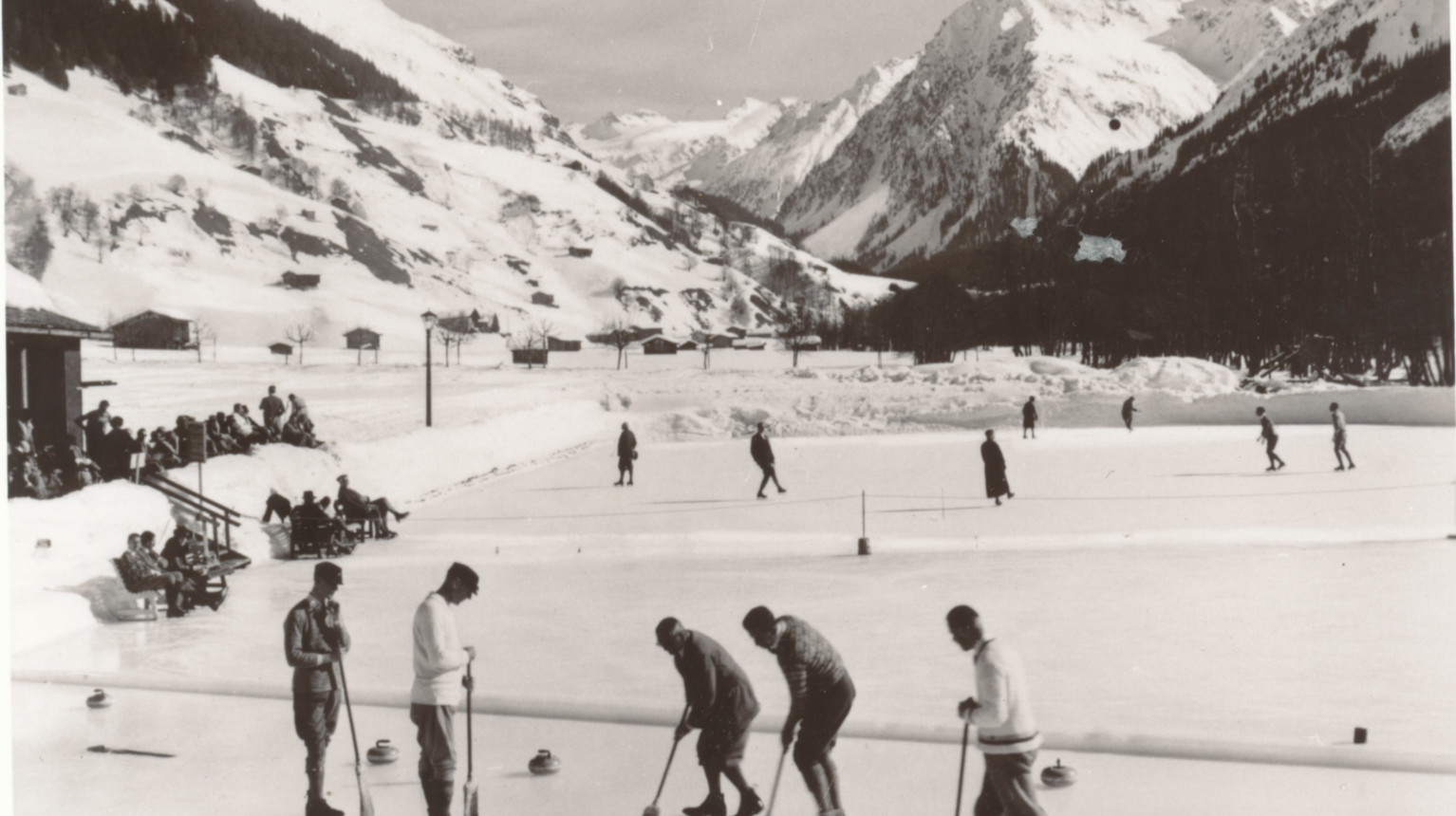 Curling in the foreground – note the curling brooms – and free skating on the back field with Canard peak and Silvretta group in the background (Archive Klosters Tourism Association / Photo Foundation Graubünden, 1930).