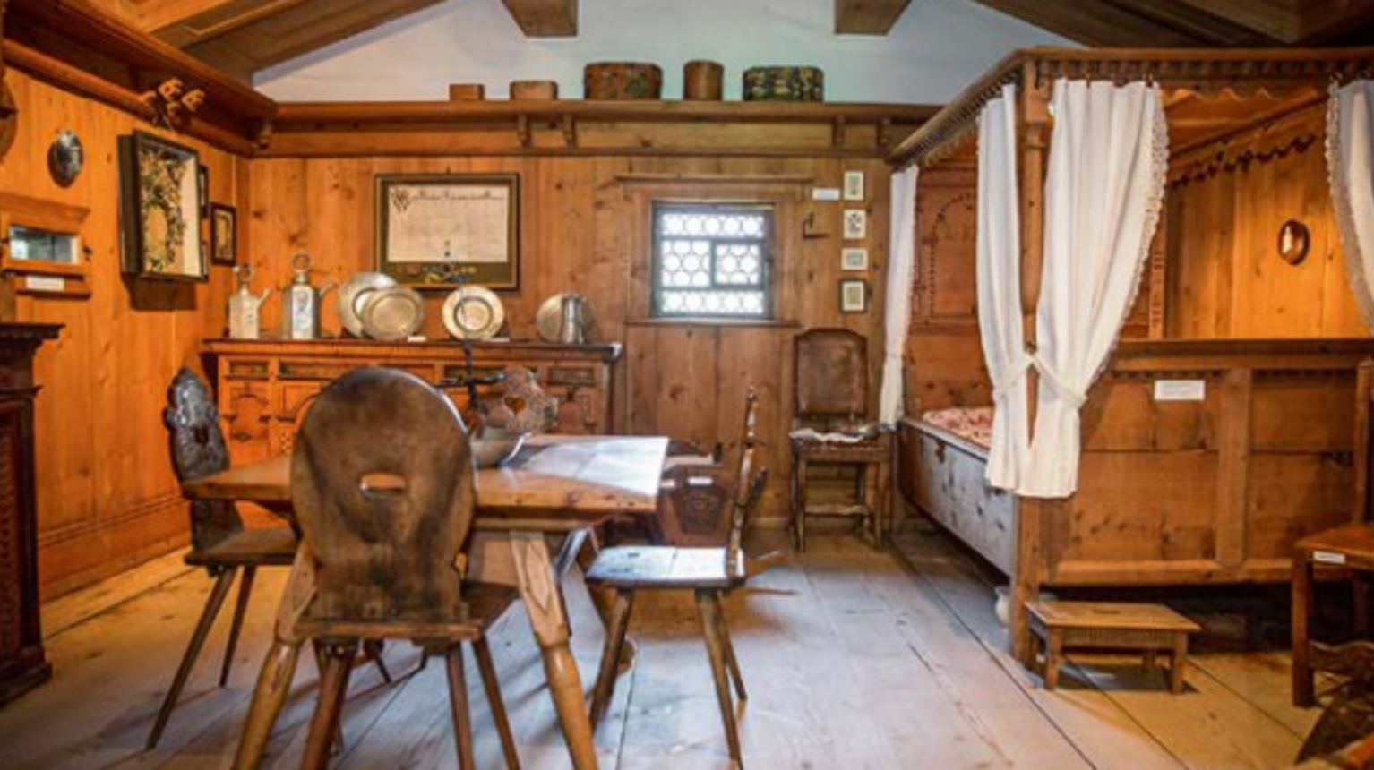 The bedroom on the first floor with table and wooden chairs in the foreground.