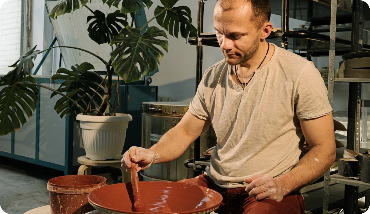 A potter glazing a large bowl in his workshop