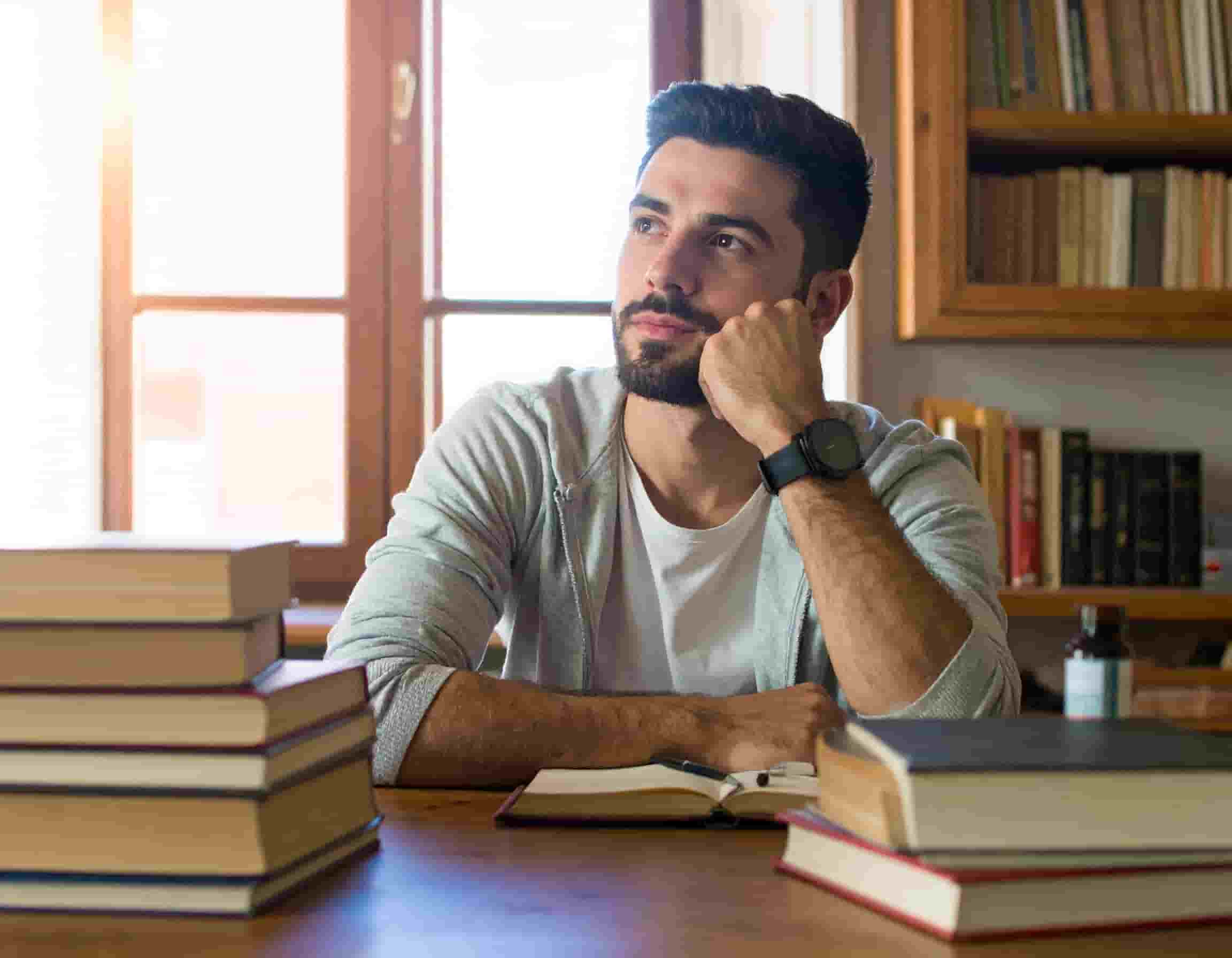 A worried young man sitting at a desk, reflecting on life choices, symbolizing awareness and prevention of Captagon addiction.