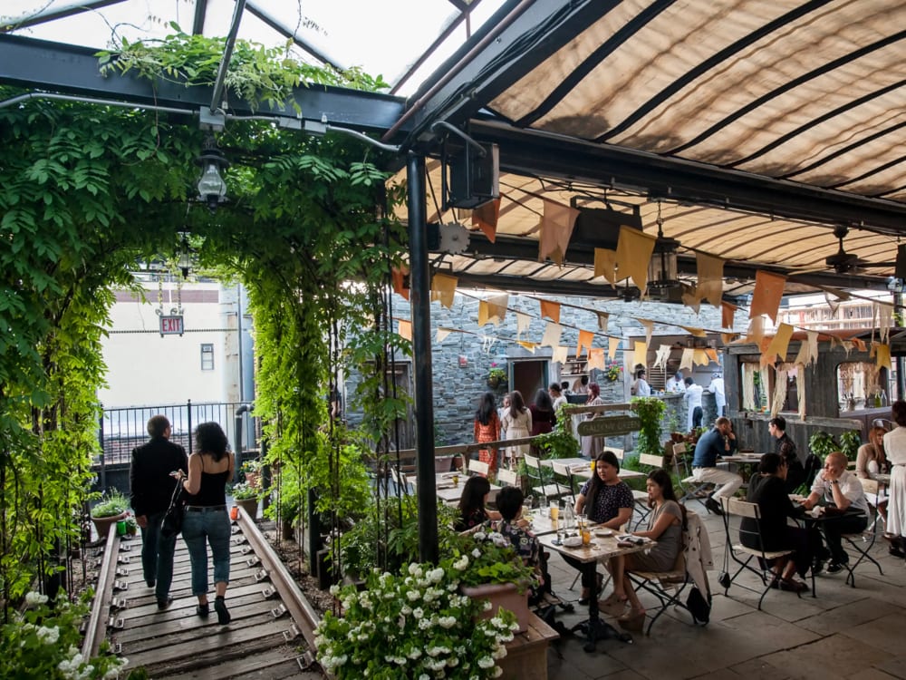 Ivy-covered trellises and string lights at a garden-style rooftop bar in Chelsea