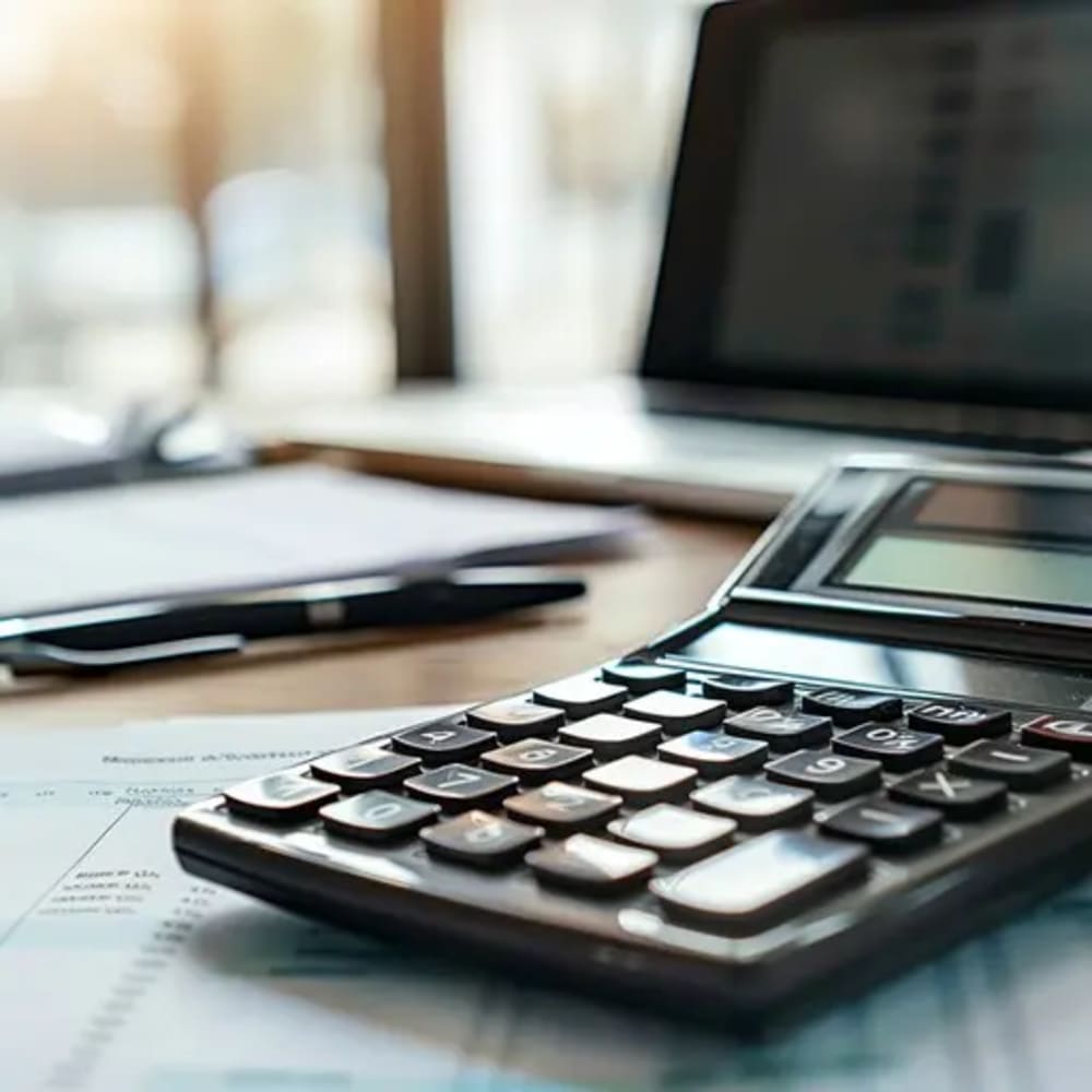 Closing documents and a calculator laid out on a table beside a laptop showing a Flatiron apartment listing