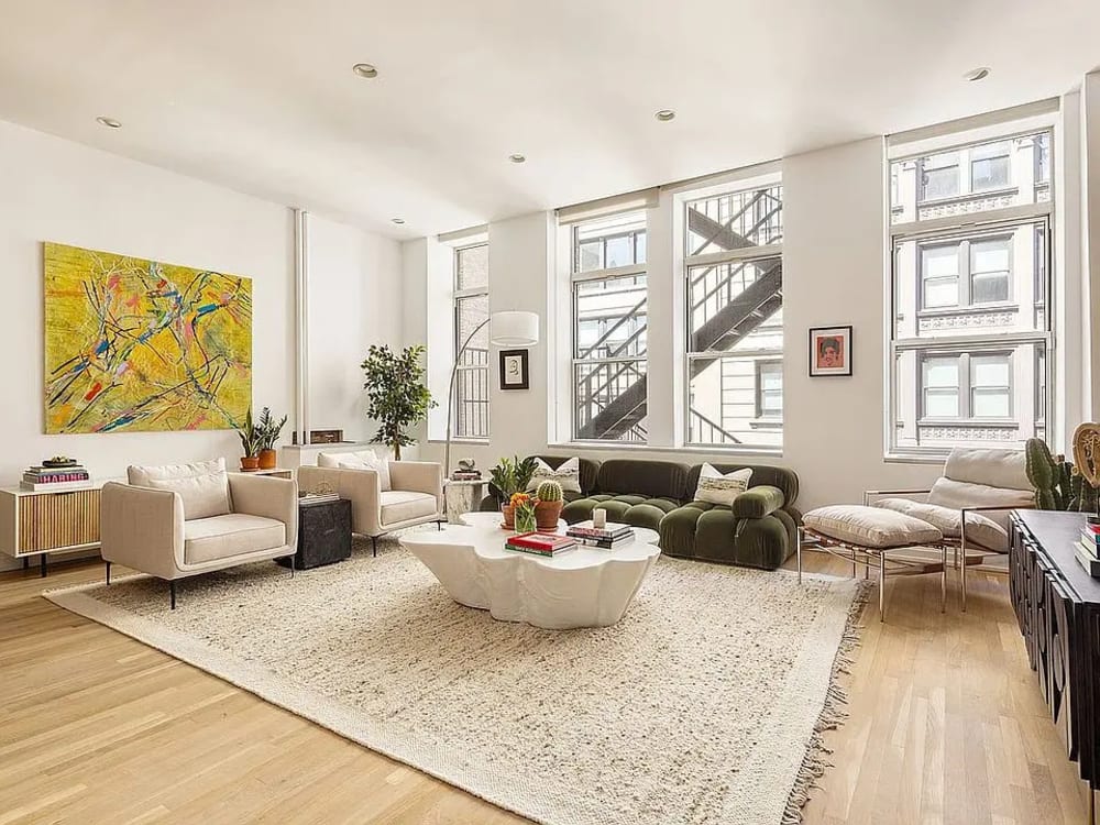 Interior of a renovated two-bedroom apartment living room with large windows and hardwood floors