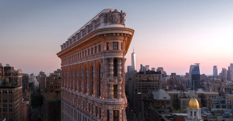 The Flatiron Building at golden hour, viewed from above with the Manhattan skyline behind it