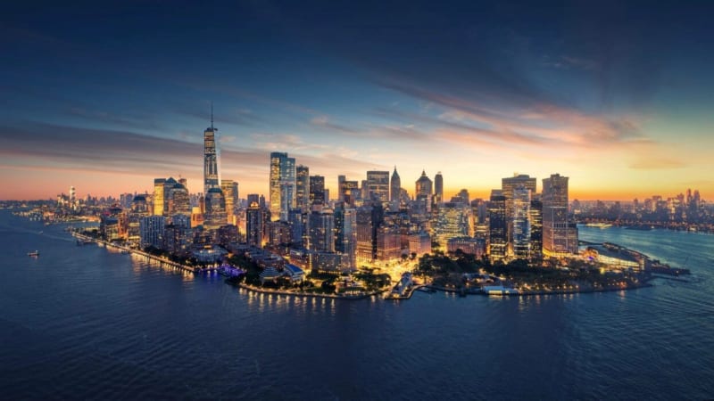 Split view of Manhattan rooftops looking from a Lower East Side walk-up toward the Financial District skyline at dusk