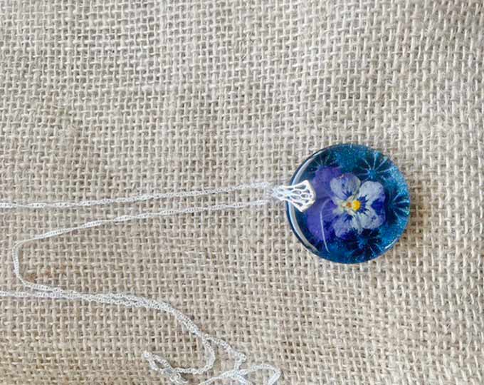 Dried pansy with holographic blue & purple background. Hung on a silver chain.