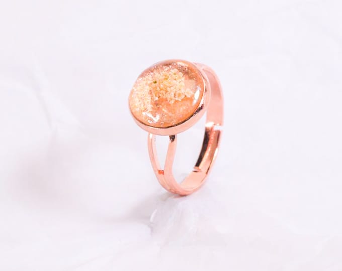 Anel de metal rosa ouro, base cintilante e flores brancas em resina