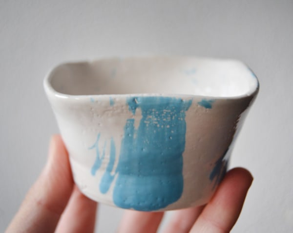 Handmade bowl, with splashes of light blue on the inside and brushstrokes on the outside