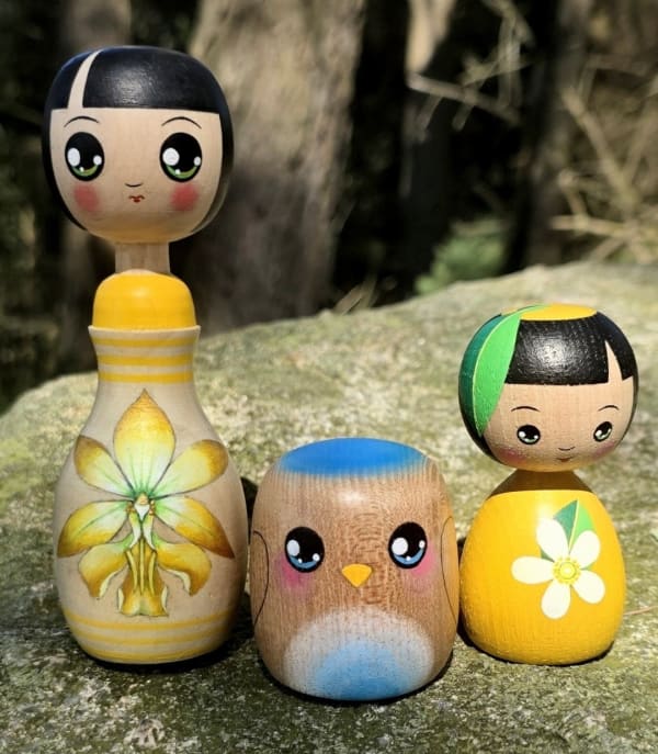 Kokeshi style doll with yellow orchid