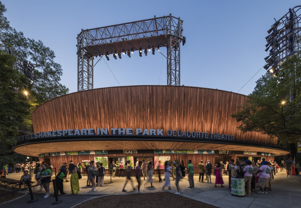 People gather outside the Delacorte Theater for Shakespeare in the Park on a sunny day.