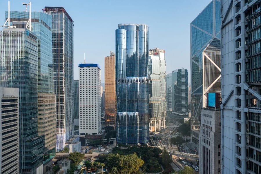 A cluster of modern skyscrapers with glass facades in a busy city center under a clear sky.