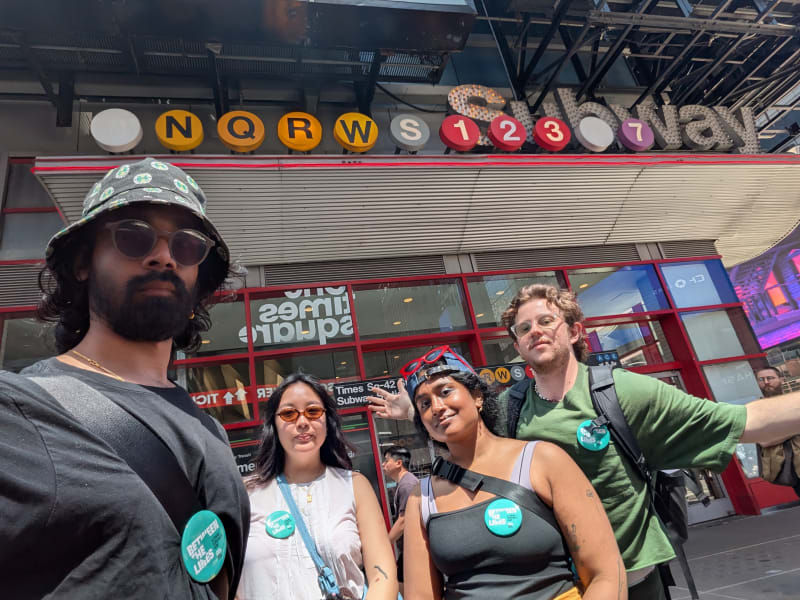 Four people pose in front of the Times Square subway station.