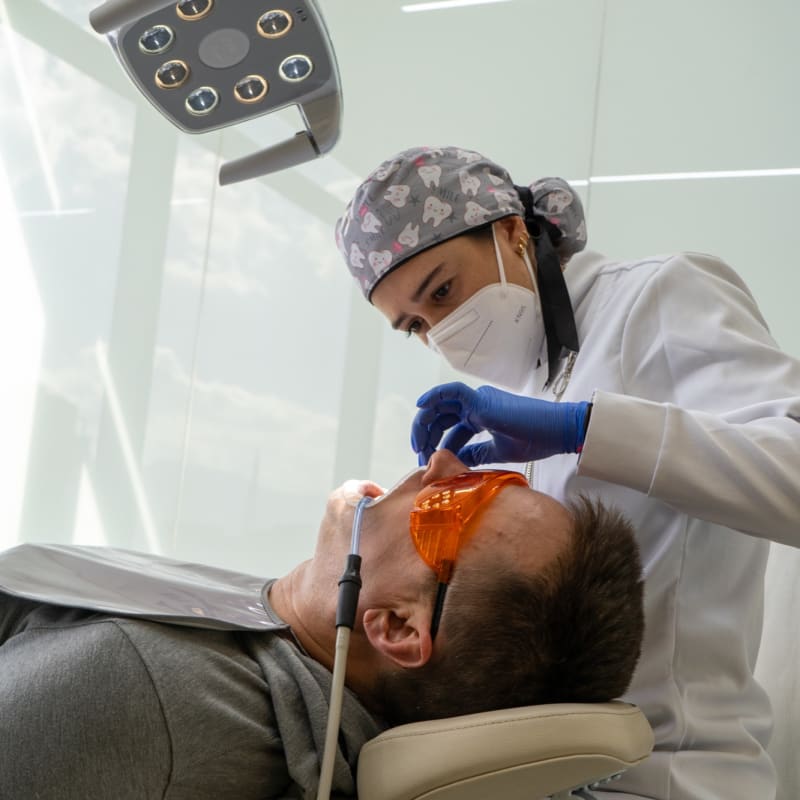 Dentist in gloves, mask and cap examining a patient in the chair at Colombia Care Dental in Medellín
