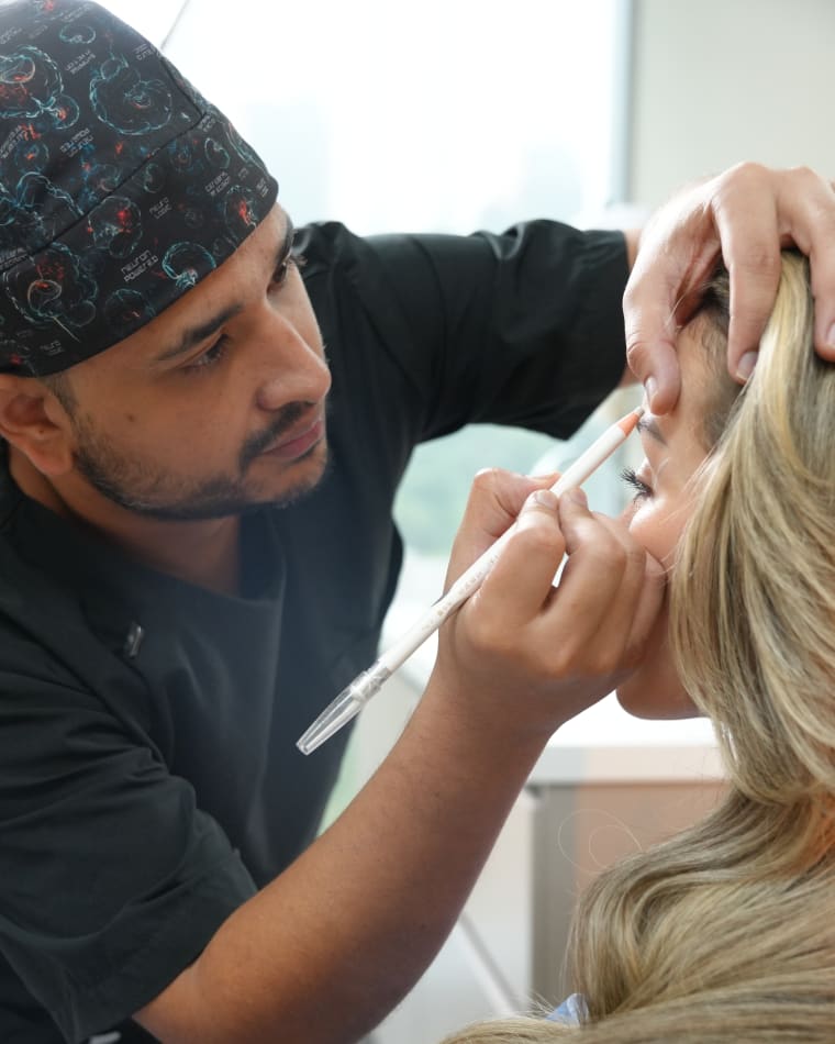 Un médico de Colombia Care trazando el diseño de las cejas de una paciente antes de su trasplante, Medellín